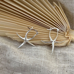 Minimalist S925 sterling silver starfish hoop earrings on natural palm leaf background