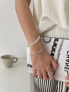 Close-up of 925 silver heart bracelet, translucent bangle, and flower ring on hand