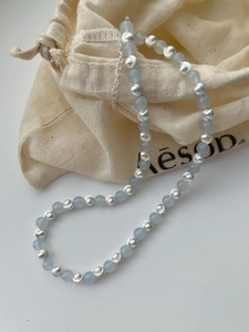 Detail of 925 silver beaded necklace with blue sapphire stones on a beige canvas pouch