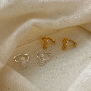 Minimalist silver and gold hoop earrings featuring vertical GOOD letter pendants