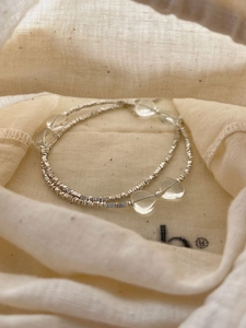 Close-up of minimalist silver beaded necklace with heart charms on linen pouch