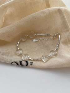 Detail of 925 silver heart bracelet with crystal beads on a textured fabric pouch
