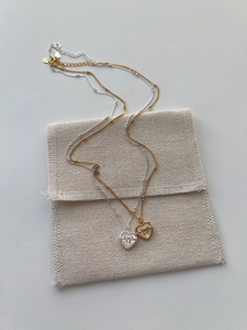 Vue détaillée des pendentifs cœur en nacre avec nœud et pochette à bijoux en tissu