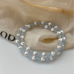 925 silver beaded necklace with light blue stones on minimalist beige linen bag