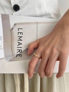 Detail of gold thin ring with round zircon and three gold beads worn with an elegant outfit