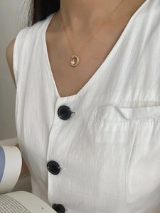 Detailed close-up of a golden moon necklace with white pearl and sparkling crystals