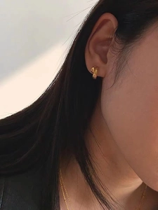 Minimalist double-loop gold stud earrings worn by model, showing refined glossy texture