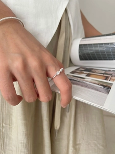 Detail of silver zirconia ring and hammered cuff bracelet on model holding a magazine