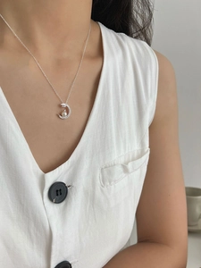 Close-up of minimalist moon pendant necklace with pearl and rhinestones on female model