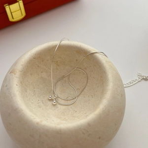 Minimalist S925 sterling silver cherry pendant necklace on a natural stone tray