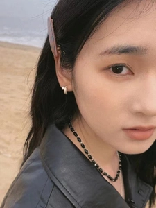 Outdoor close-up of a minimalist black beaded necklace with silver accents on a model
