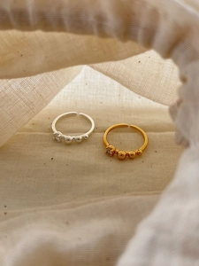 Detail view of gold and silver S925 rings with mini zircon and small beads on fabric