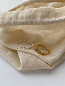 Detail of adjustable gold and silver rings with zircon inlay and bead design