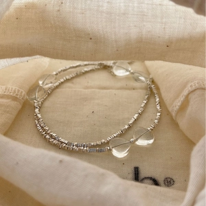 Handcrafted silver beaded necklace with crystal heart pendants on a linen pouch