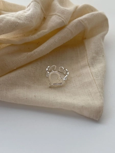 Détail d'une bague en argent 925 épaisse avec cœur évidé sur fond en lin naturel