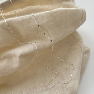 Chic 925 sterling silver necklace featuring small polished heart charms on a linen bag