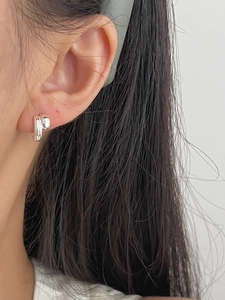Close-up of minimalist silver twisted double hoop earrings worn on a model's ear
