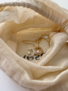 Close-up of S925 sterling silver moon pearl necklaces in a linen gift pouch