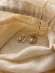 Detailed view of crescent moon pendants with pearls and zircons in gold and silver