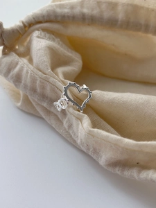 Gros plan détaillé d'une bague coeur en argent avec bords perlés sur un sachet