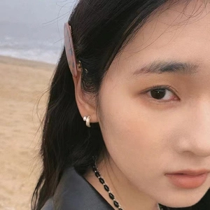 Minimalist silver hoop earrings and marble texture hair clip on a model at the beach