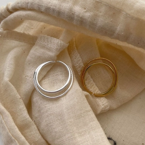 Minimalist double layer 925 sterling silver rings in gold and silver on a beige fabric