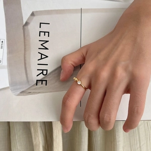 Minimalist gold ring with zircon stone and bead details shown on a model's hand