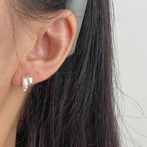 Minimalist silver geometric stud earrings shown as a side close-up on a female model