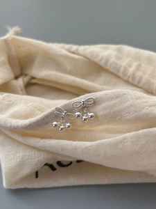 Λεπτομέρεια από ασημένια σκουλαρίκια S925 με φιόγκο και χάντρες σε υφασμάτινη θήκη