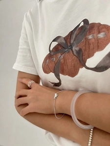 Detail of 925 sterling silver croissant snake chain bracelet paired with minimalist rings
