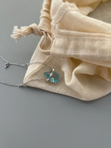 Detail of 925 sterling silver bamboo necklace with a light blue pear-cut sapphire pendant