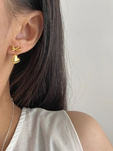 Gros plan de boucles d'oreilles nœud dorées avec pendentifs cœur sur mannequin