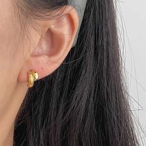 Minimalist gold bean earrings featuring parallel streamlined curves on model's ear