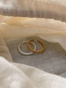 Detailed view of gold and silver twisted hoop earrings on a soft fabric pouch