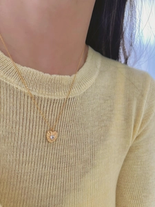 Detail of heart pendant with radiant texture and zircon on a gold necklace