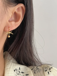 Detailed view of gold knot earrings with hanging bead on model for an elegant look