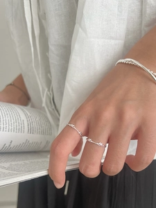 Detail of 925 sterling silver bow knot rings and minimalist bracelet on model hand