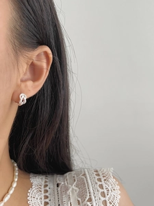 Détail de boucles d'oreilles argentées torsadées sur modèle pour un look élégant