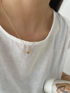 Close-up of a delicate gold heart and key pendant necklace on a minimalist silver chain