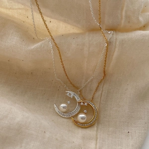 Minimalist crescent moon pearl necklace in gold and silver finish on linen fabric