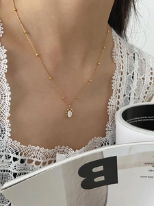 Gros plan sur un collier vintage doré avec pendentif ovale en nacre et chaîne perlée