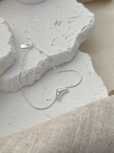 Detail of 925 sterling silver croissant charm on a delicate snake bone chain bracelet