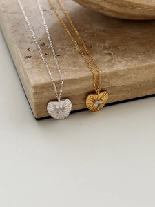 Macro detail of gold and silver heart pendants with radiating texture and zircon stones