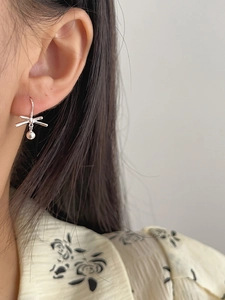 Detail of 925 sterling silver lucky knot earrings on model ear for daily wear