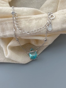 Detail of 925 sterling silver necklace featuring a blue teardrop gemstone pendant
