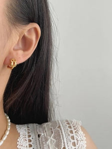 Détail de boucles d'oreilles torsadées dorées avec finition polie portée sur un modèle
