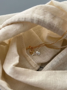 Detail of silver and gold heart lock necklaces with key pendants on beige linen