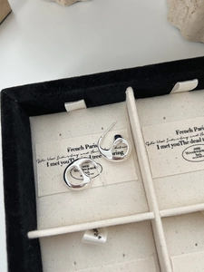 Detail of minimalist silver irregular curved earrings on premium jewelry box display