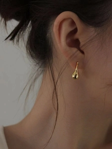 Close-up of minimalist gold teardrop earrings with a high-polish finish on a model
