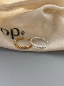 Close-up of gold and silver S925 sterling silver twisted rings on a fabric pouch